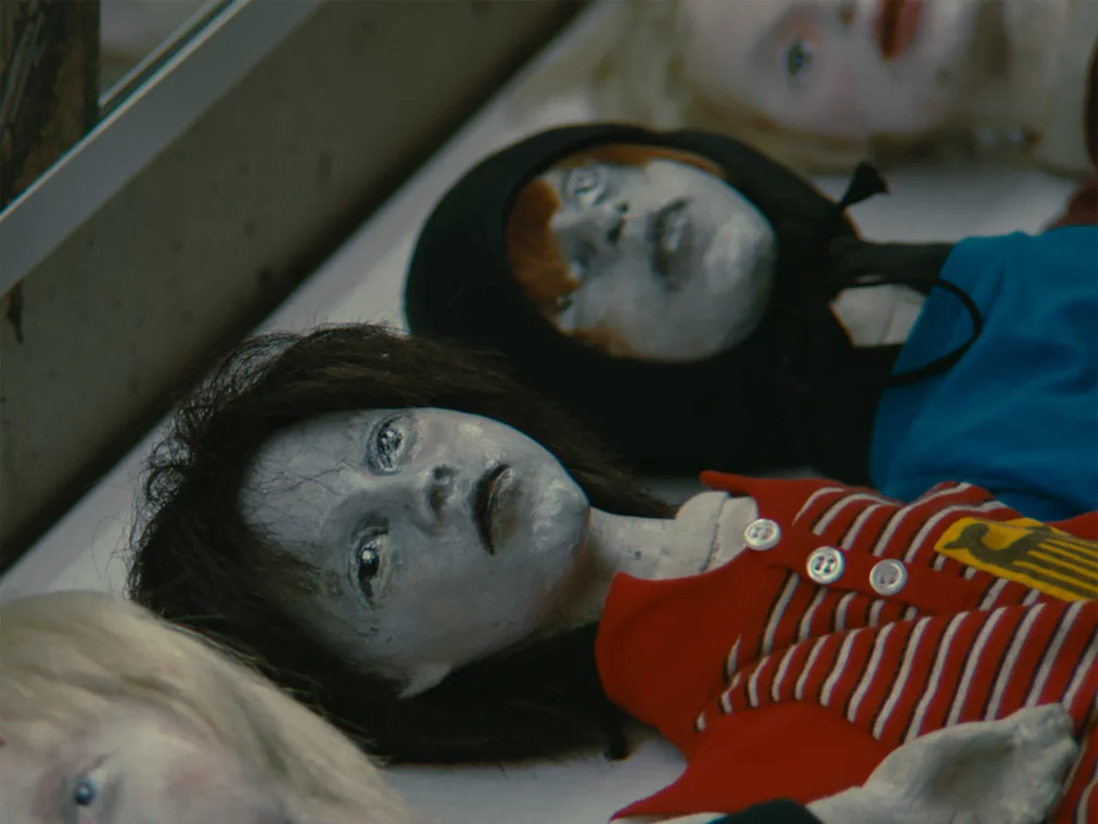 Various dolls with gray faces are lined up next to each other.