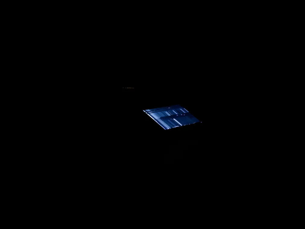 A glowing screen lies on the floor in a dark room.