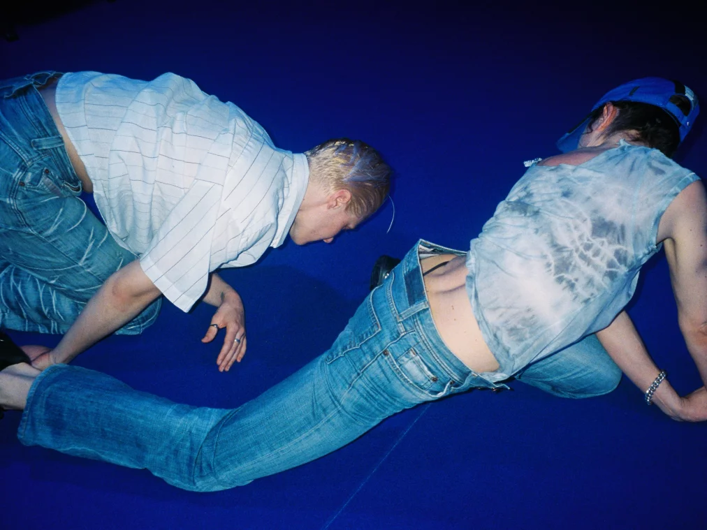 Two people are lolling on a blue carpet.