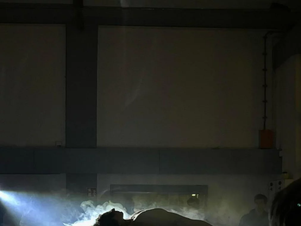 Eine Person liegt auf dem Bach eines Autos. Ein Spot-Light ist auf sie gerichtet.